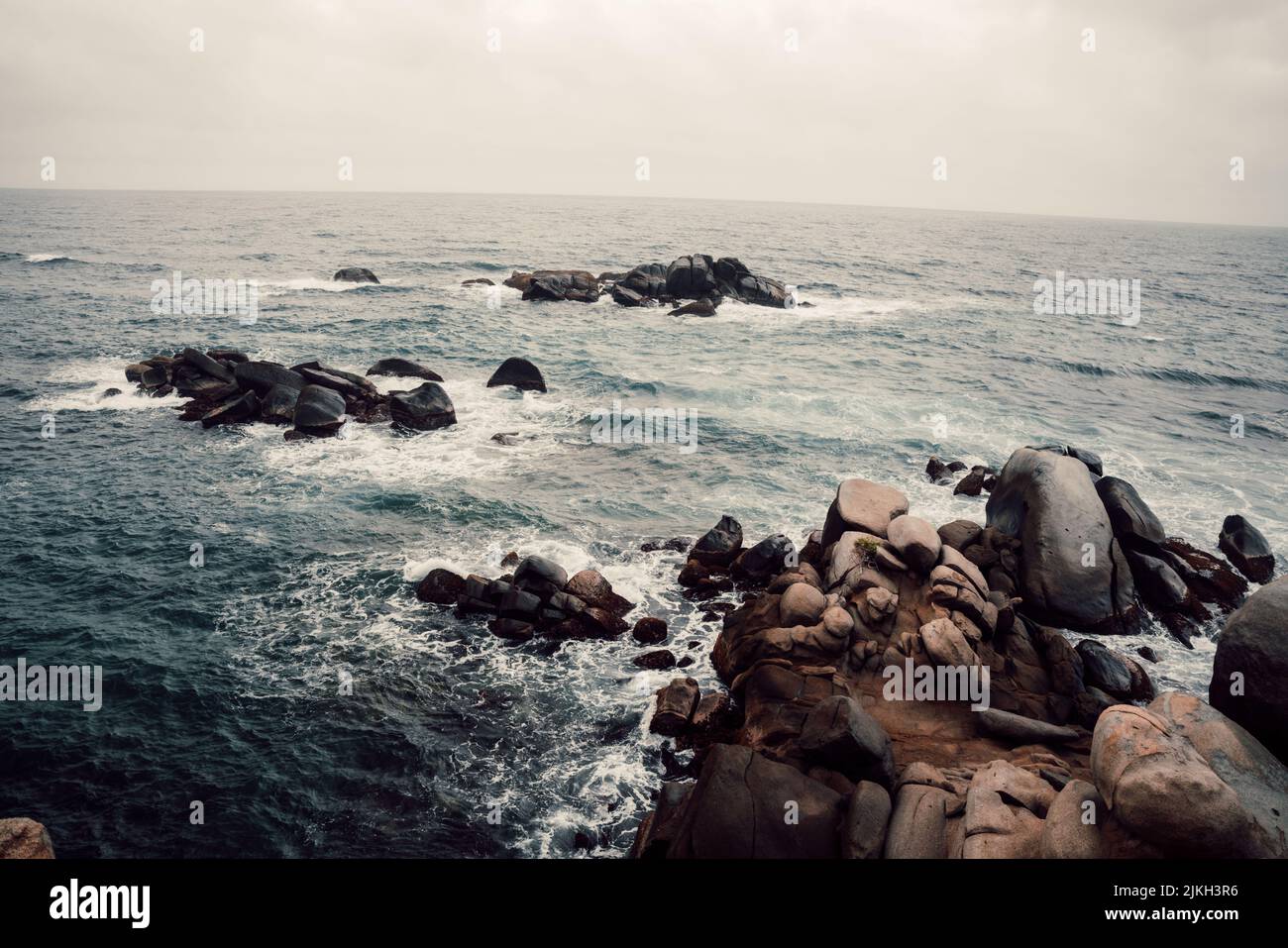 Una vista delle onde di mare burrascoso che si schiantano nelle rocce Foto Stock