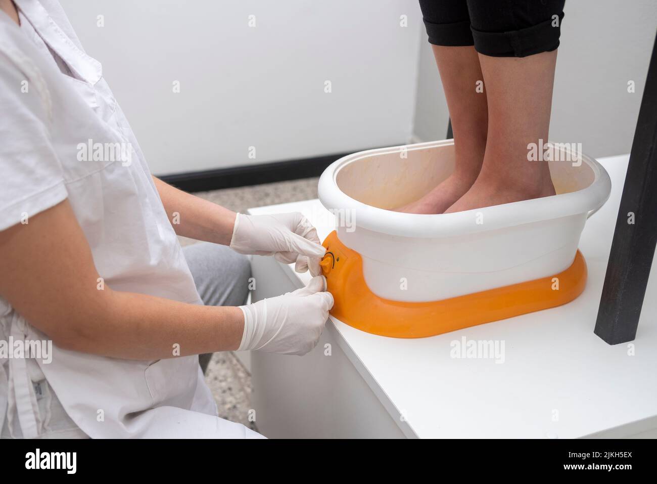 Una donna che esegue un trattamento di podiatria con una macchina per cera in un centro estetico Foto Stock
