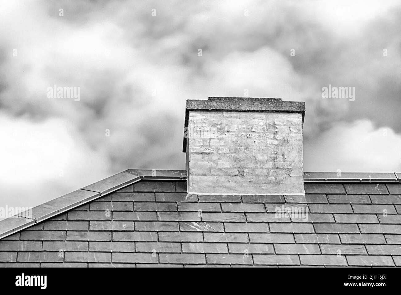 Un colpo in scala di grigi di un camino sul tetto di una nuova casa Foto Stock