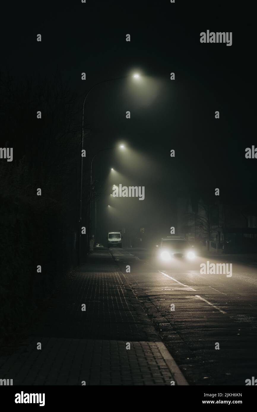 Uno scatto verticale di un'auto sulla strada a tarda notte Foto Stock