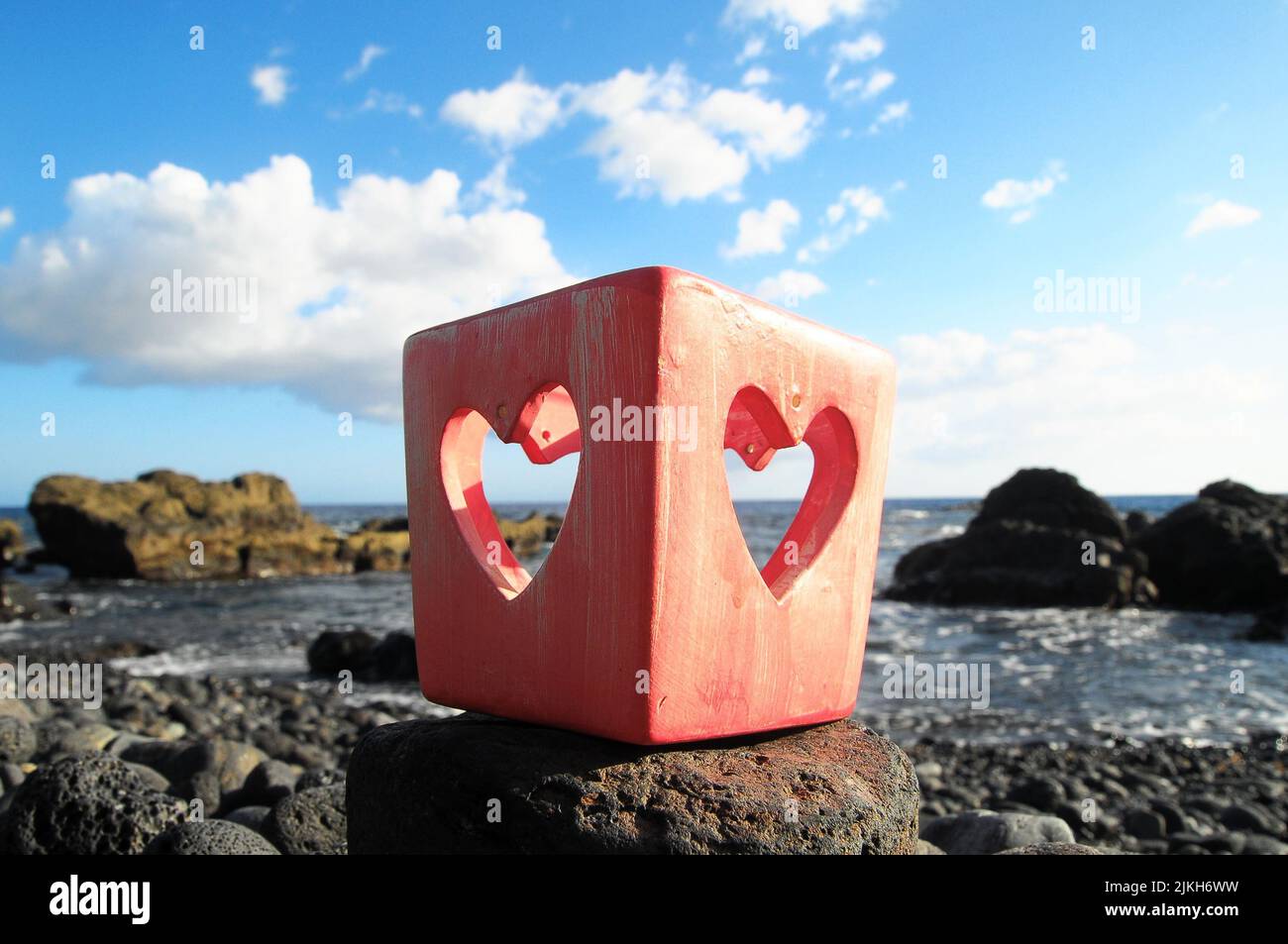 Portacandele a forma di cuore rosso vicino all'oceano Foto Stock