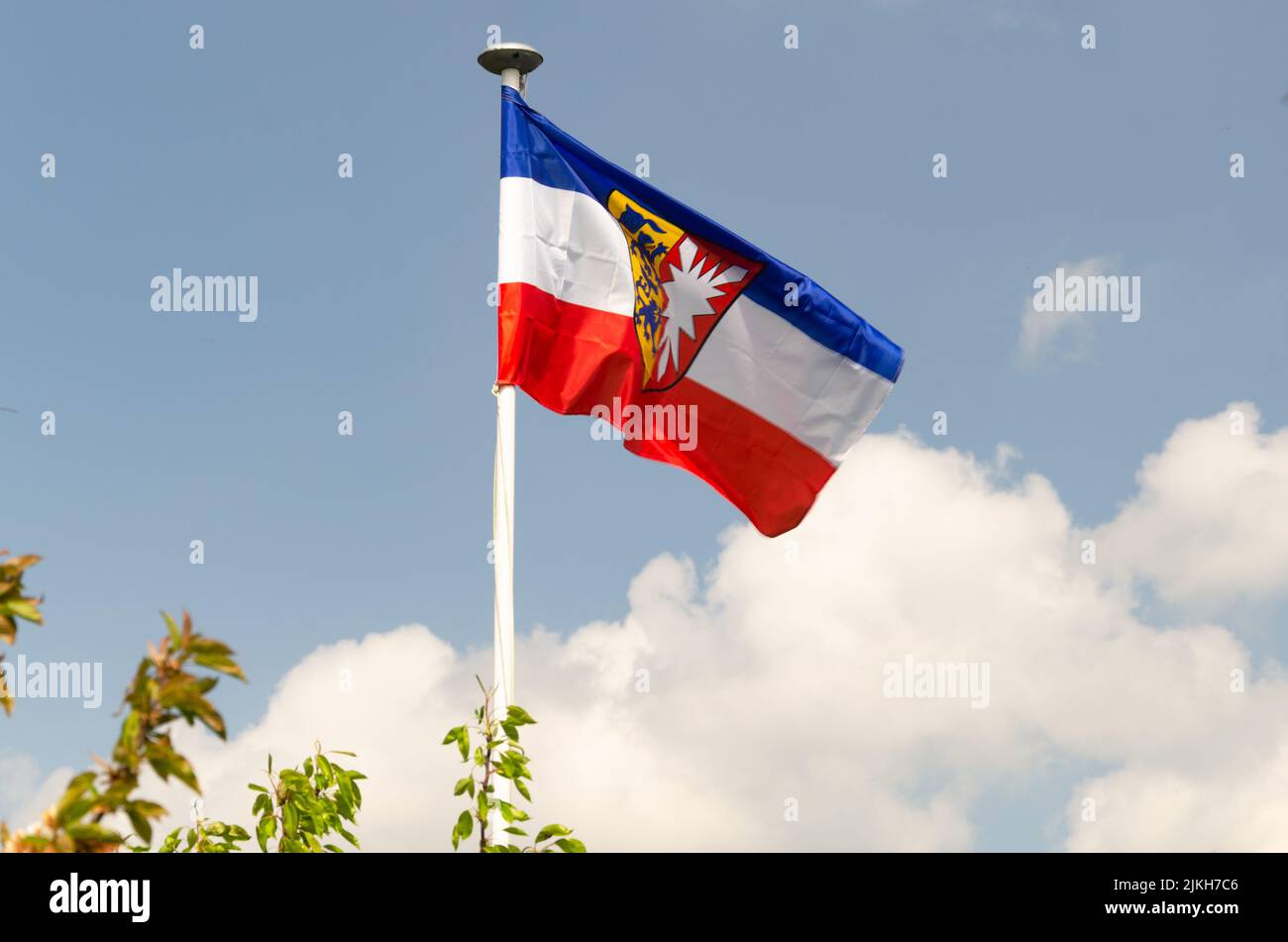 La bandiera sventolante dello Stato dello Schleswig-Holstein in Germania contro un cielo nuvoloso e blu Foto Stock