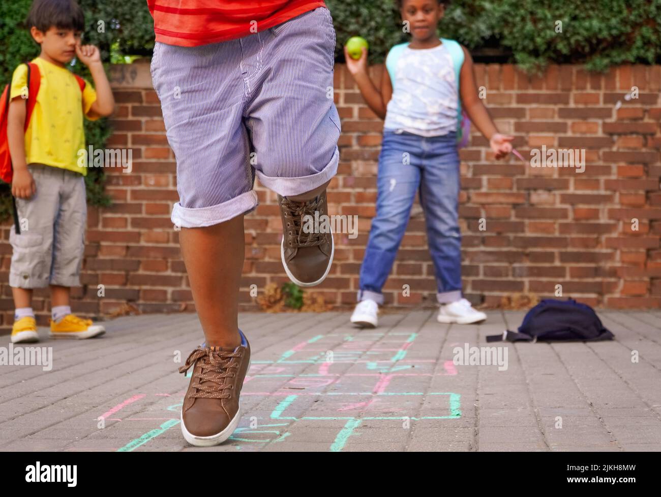 bambini multietnici che giocano a hopscotch nel parco giochi della scuola. torna al concetto di scuola. gruppo di bambini multietnici Foto Stock