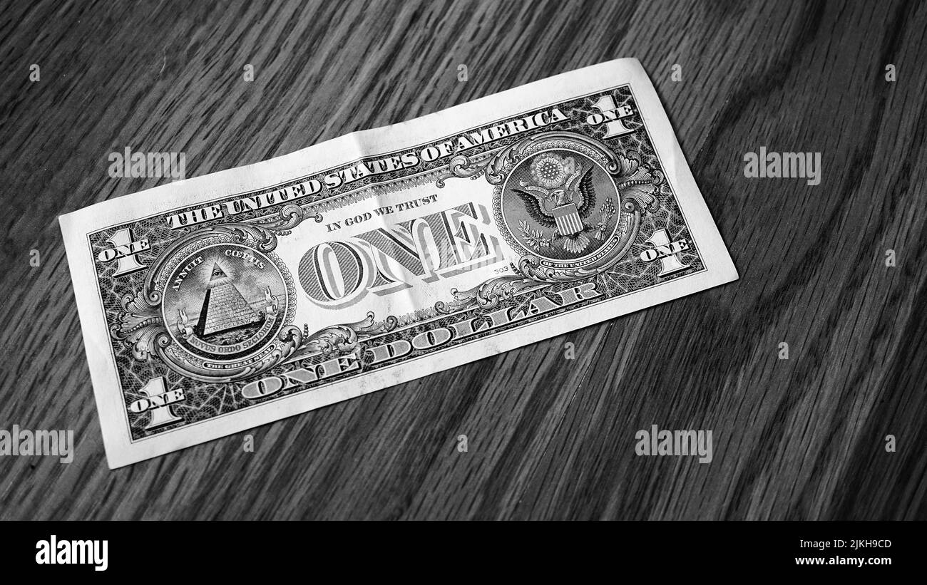 Un colpo in scala di grigi di una fattura americana del dollaro su un tavolo di legno Foto Stock