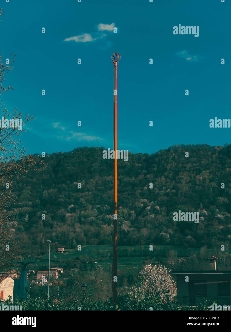 Un colpo verticale di scaricatore di fulmini contro il cielo blu con foreste di montagna sullo sfondo Foto Stock