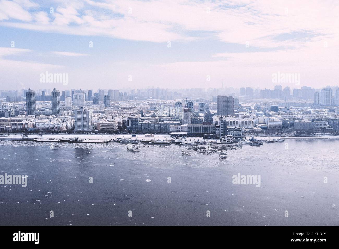 Una bella vista di una città innevata con barche in un lago ghiacciato Foto Stock