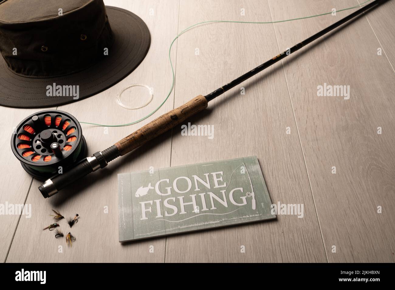 Segno di pesca andato, pesca del mosca attrezzatura, su uno sfondo di legno chiaro con spazio di copia Foto Stock