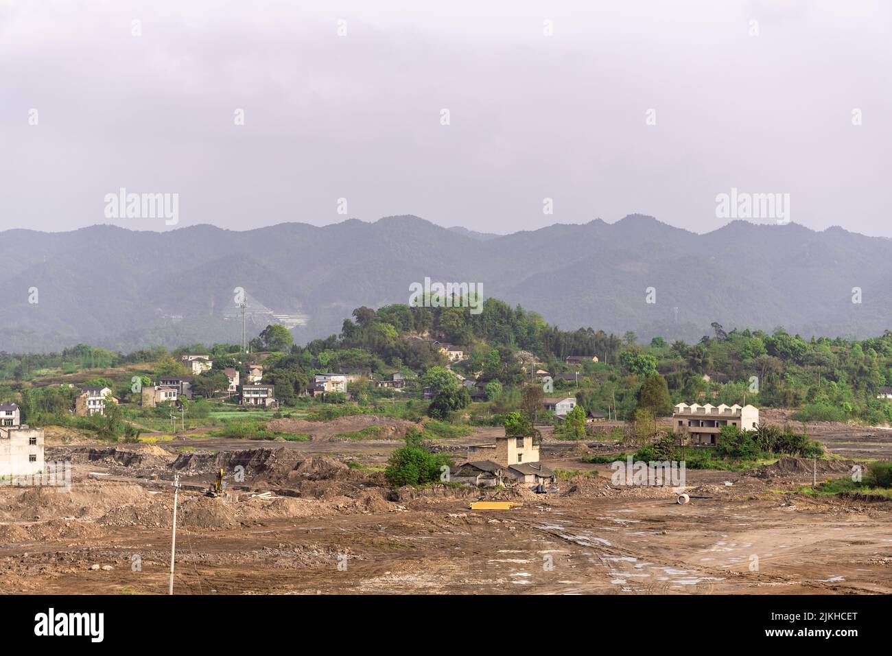 Un terreno roccioso tumble-down con alcuni edifici sullo sfondo di montagne boschive Foto Stock