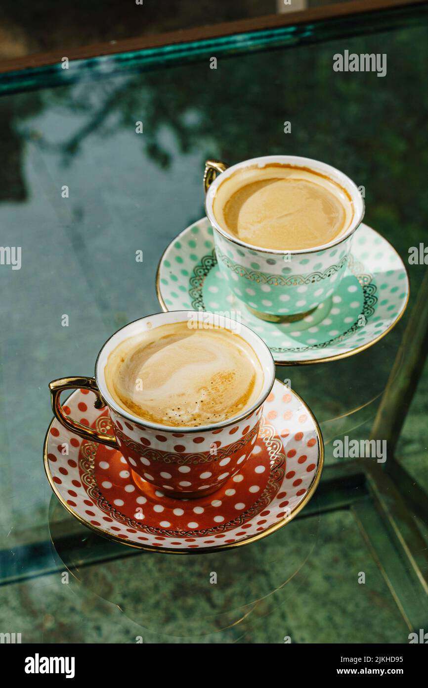Un primo piano verticale di caffè in vasetti vintage rossi e blu su un tavolo di vetro Foto Stock