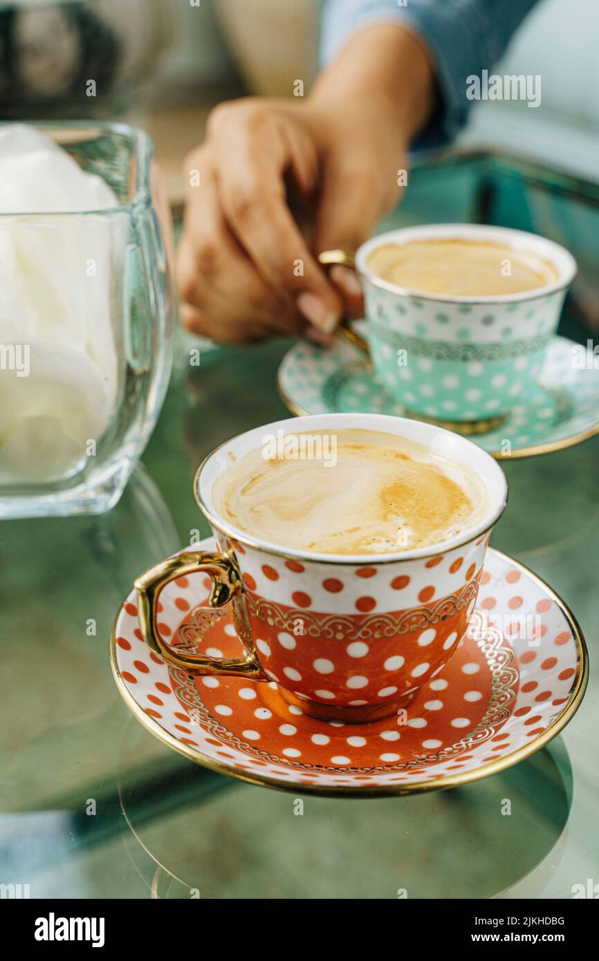 Un primo piano verticale di caffè in vasetti vintage rossi e blu su un tavolo di vetro Foto Stock