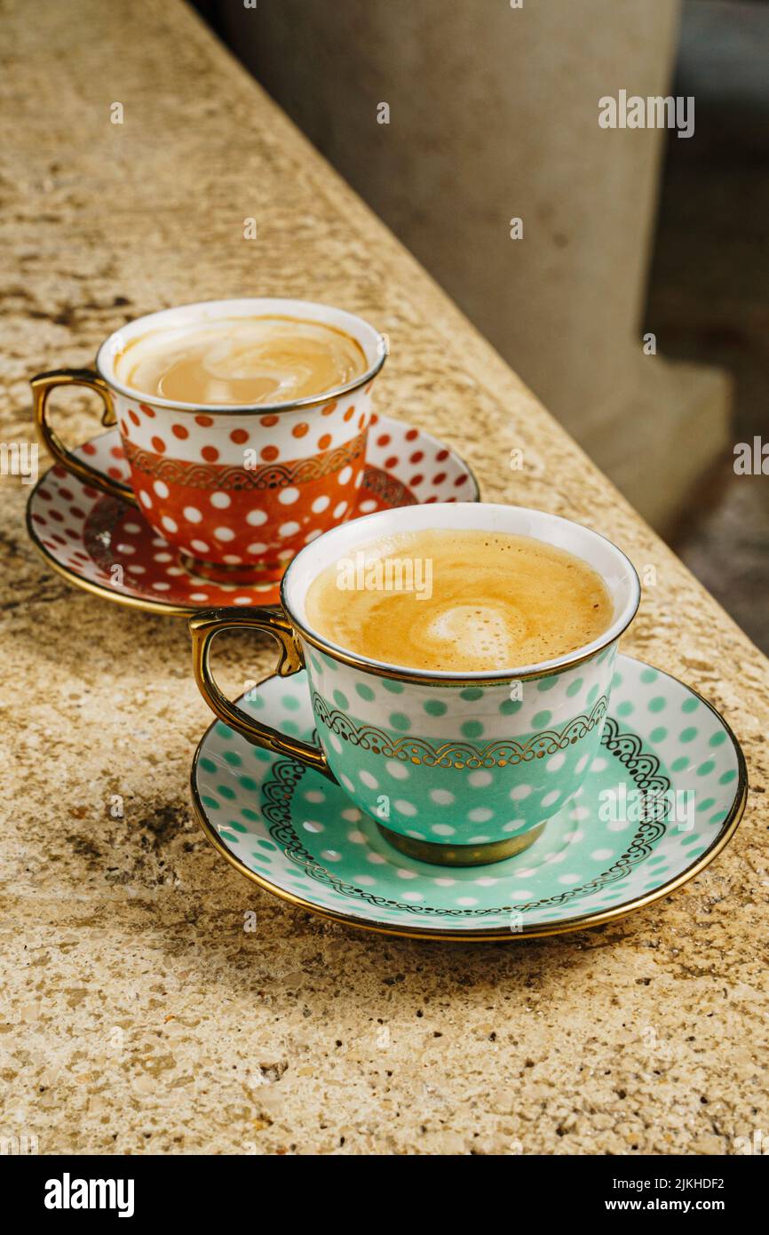 Un primo piano verticale di caffè in tazze rosse e blu su un tavolo Foto Stock