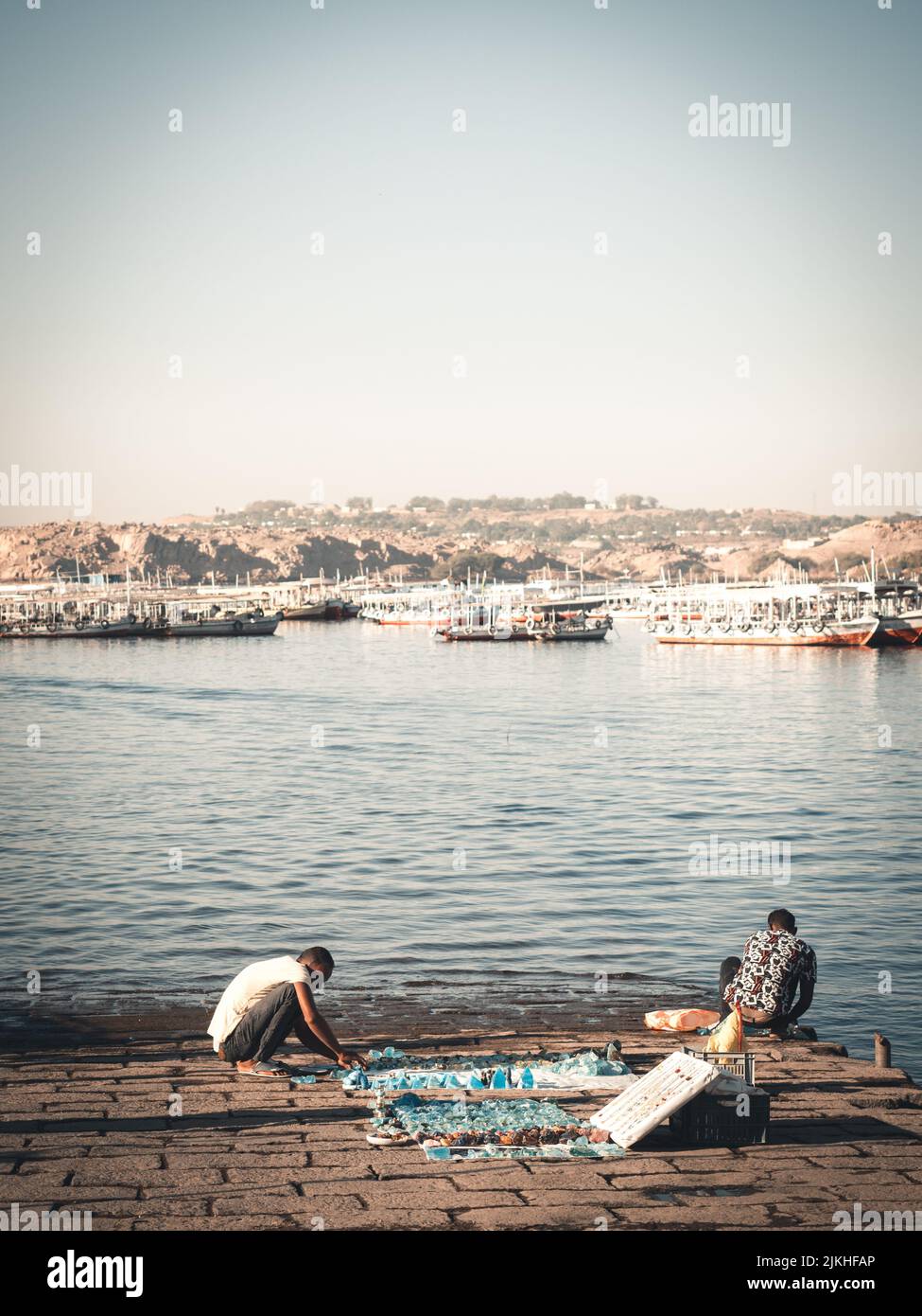 Una vista della gente su una riva di un lago Nasser con le barche nel sud dell'Egitto Foto Stock
