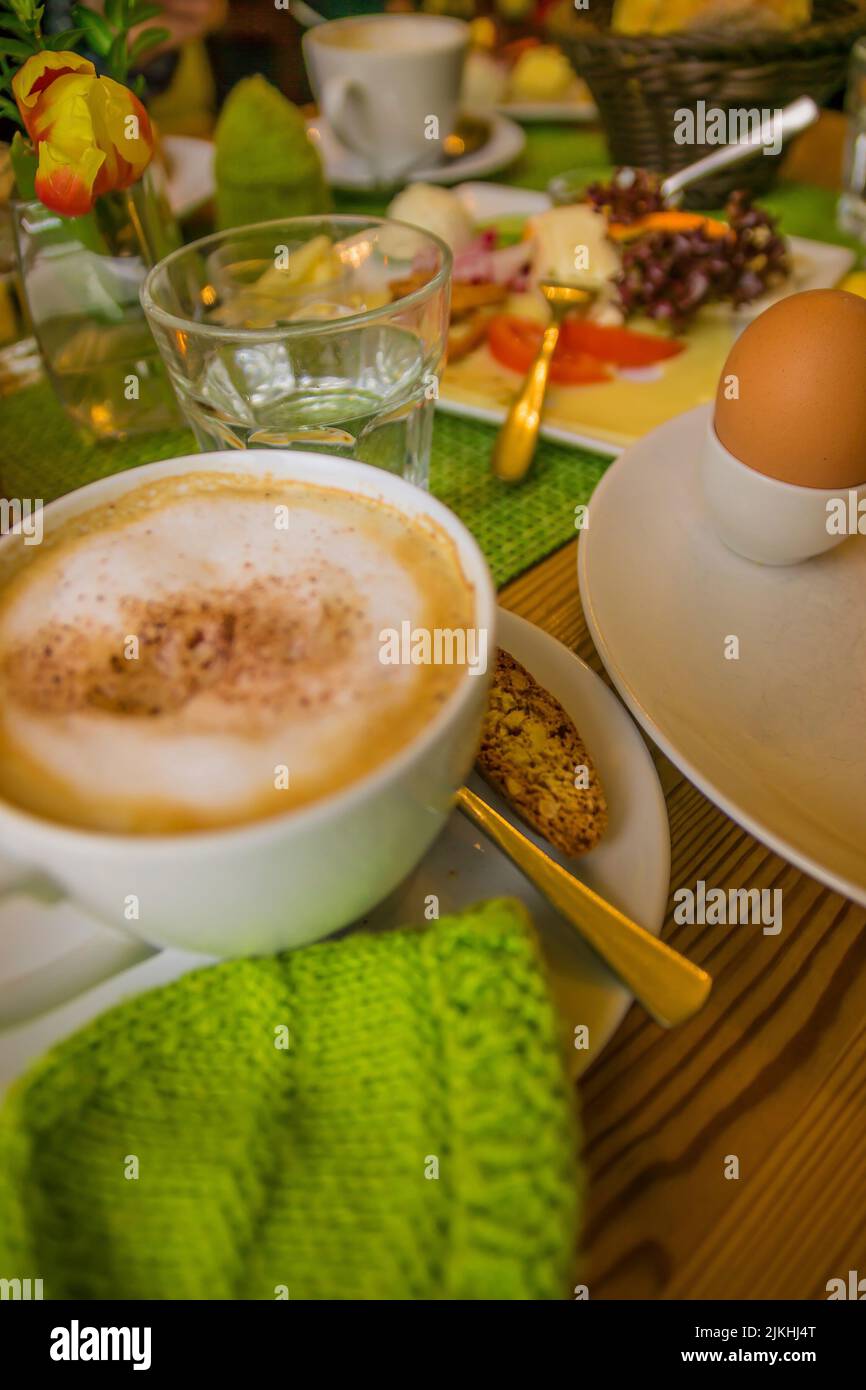 Un tavolo per la colazione con cappuccino e ingredienti freschi. Foto Stock