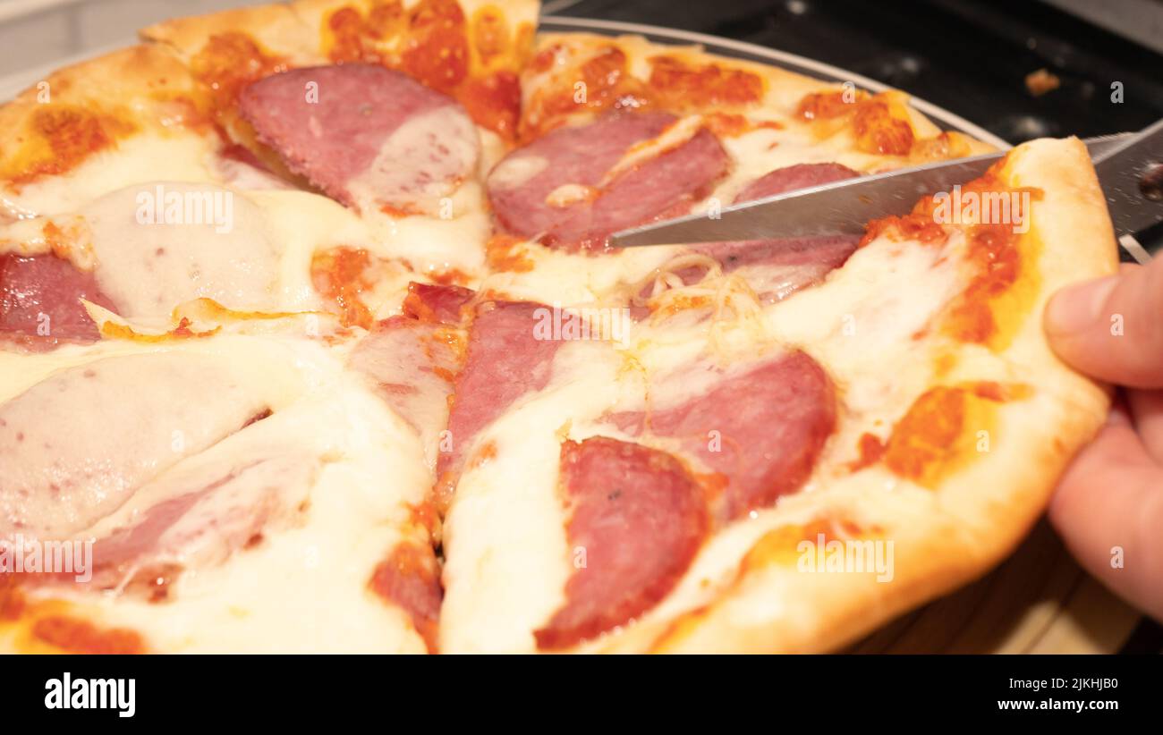 Pizza al peperone con mozzarella, salame, pomodori, pepe, spezie e basilico fresco. Pizza italiana Foto Stock