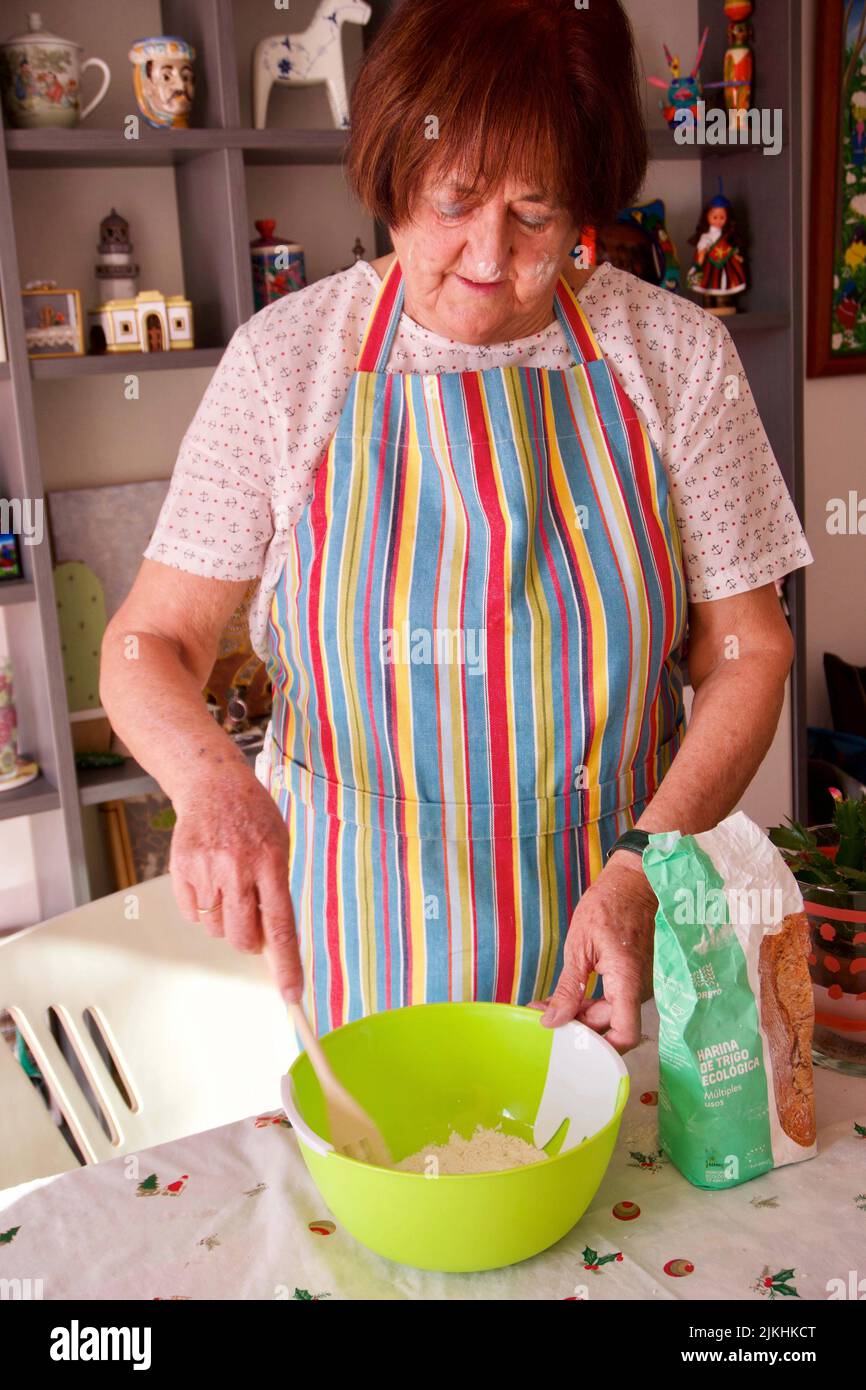 Un colpo verticale di una donna caucasica matura che cucinava a casa con farina e uova, Barcellona, Spagna Foto Stock