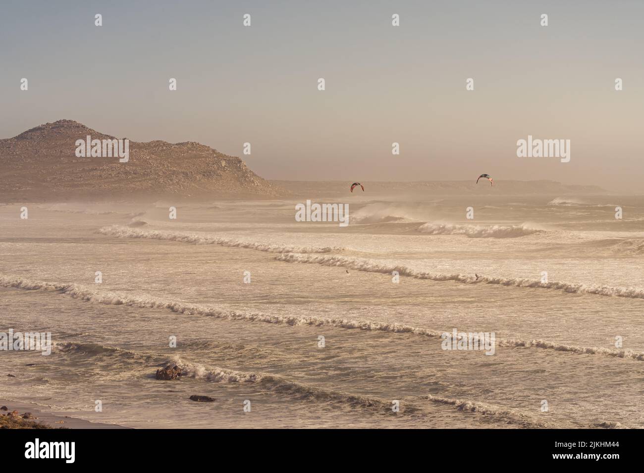 Due paracadute che volano sull'oceano ondulato e sulle scogliere Misty, vicino a Città del Capo Foto Stock