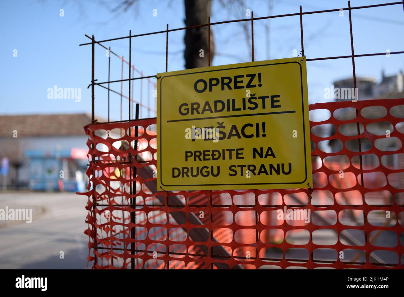 Un segnale di avvertimento giallo di sicurezza su un cancello rosso all'aperto Foto Stock