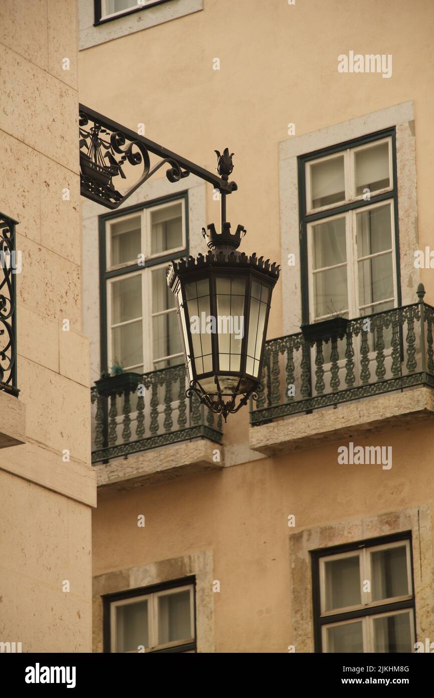 Una foto verticale di una vecchia lampada su una strada a Lisbona, Portogallo, con edifici sullo sfondo Foto Stock