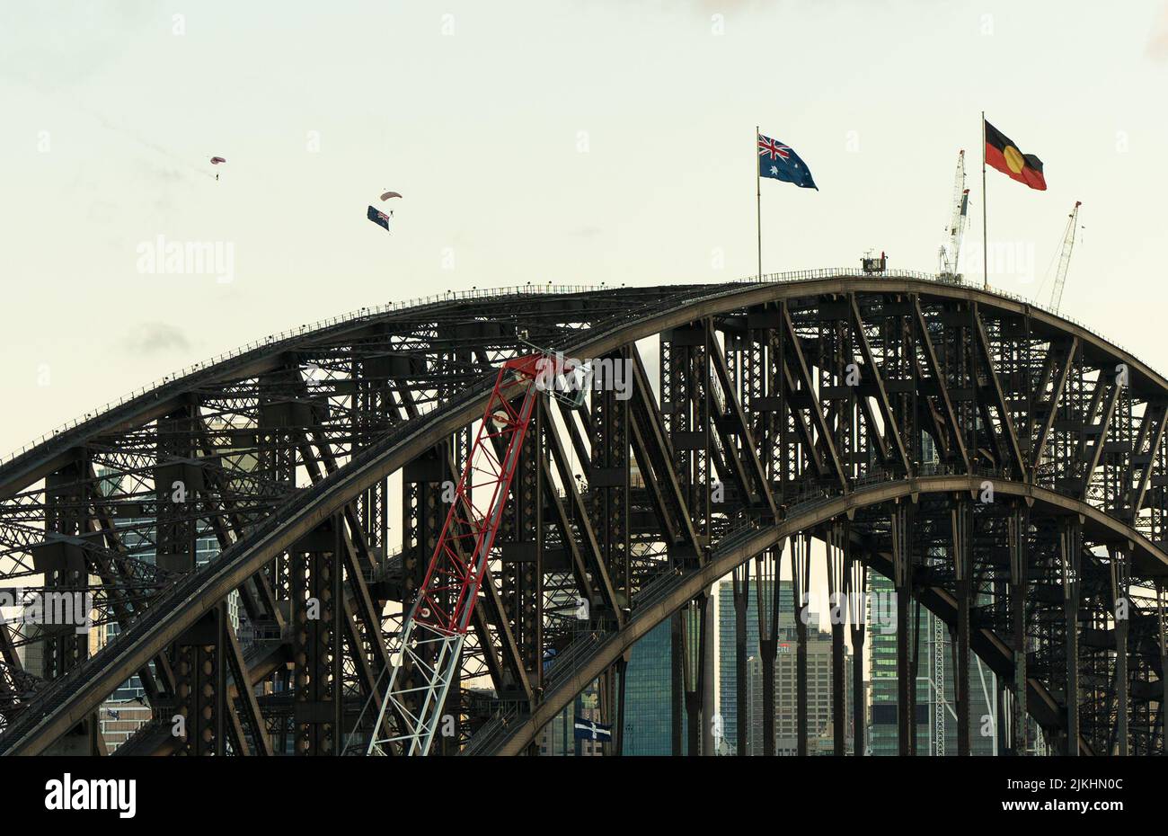 Bandiera australiana e bandiera aborigena sul Sydney Harbour Bridge con paracadutisti. Foto Stock