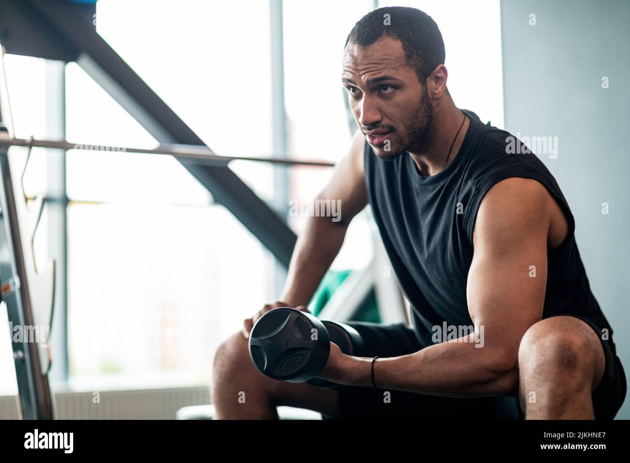 Muscular Black Young Man che si esercita con Dumbbell nella moderna palestra Foto Stock
