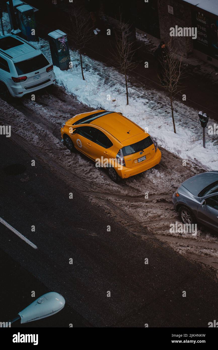 Un colpo verticale di una Toyota gialla parcheggiata in strada durante l'inverno a Vancouver, Canada Foto Stock