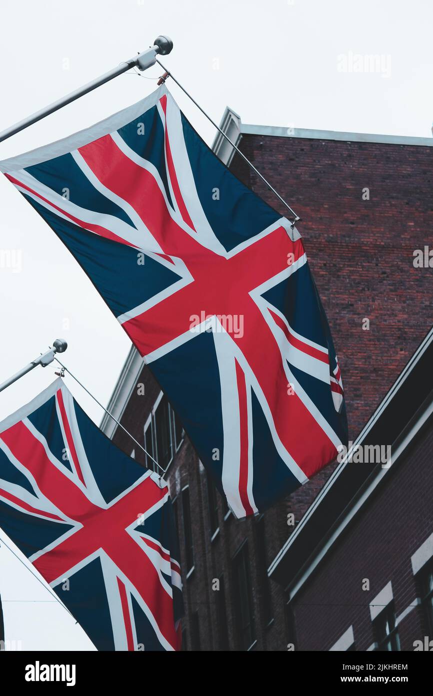 Una foto verticale di due bandiere del Regno Unito attaccate ad un edificio Foto Stock