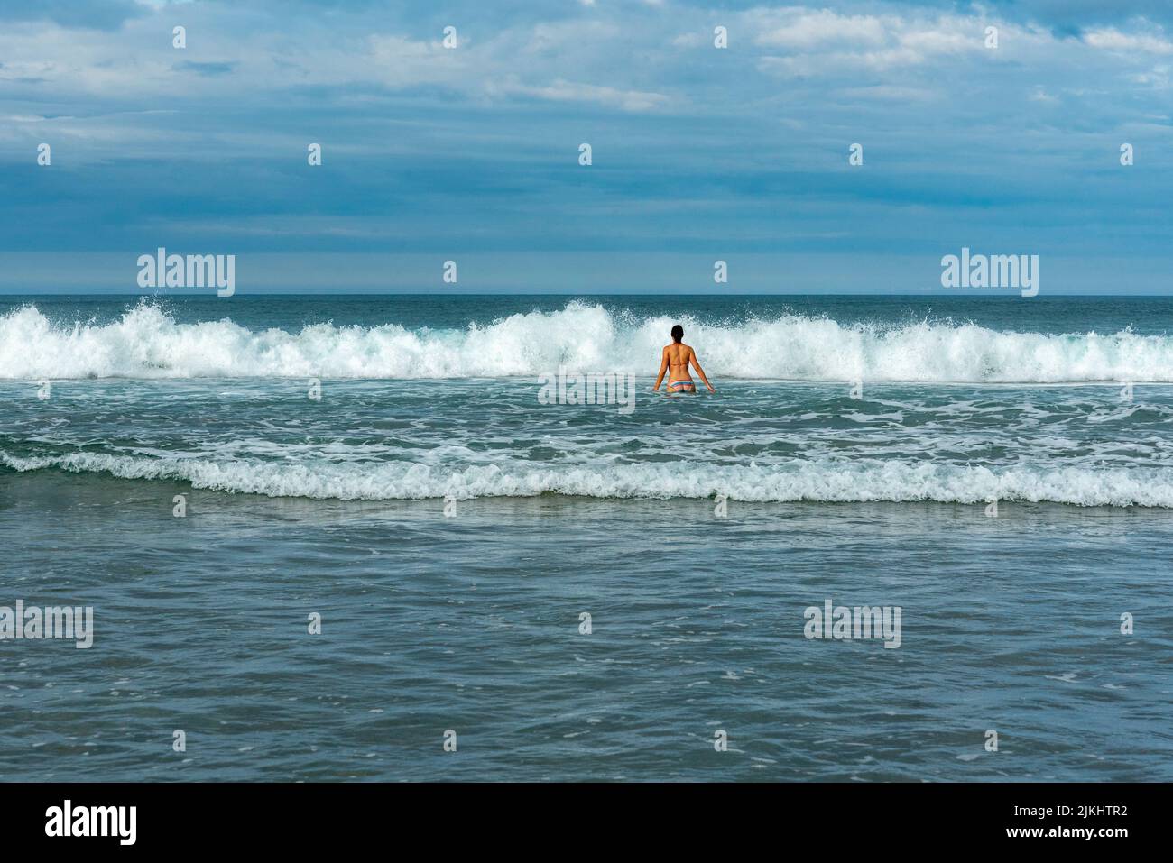 Una donna che bagna nelle onde dell'oceano Pacifico, la Grande Isola della barriera Foto Stock