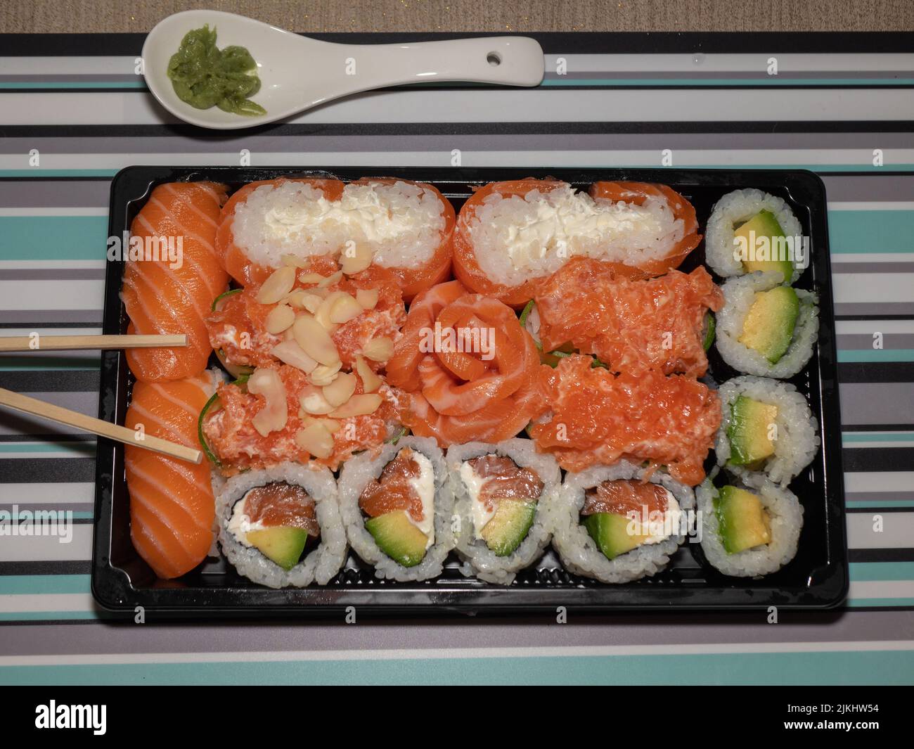 Cucina giapponese, consegna cibo a Coronavirus, sushi in un contenitore nero su un tavolo di legno, consegna e ordine Foto Stock