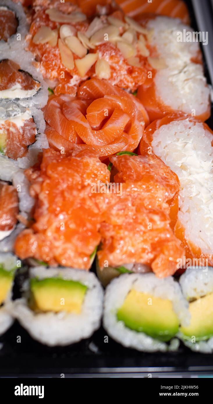 Cucina giapponese, consegna cibo a Coronavirus, sushi in un contenitore nero su un tavolo di legno, consegna e ordine Foto Stock