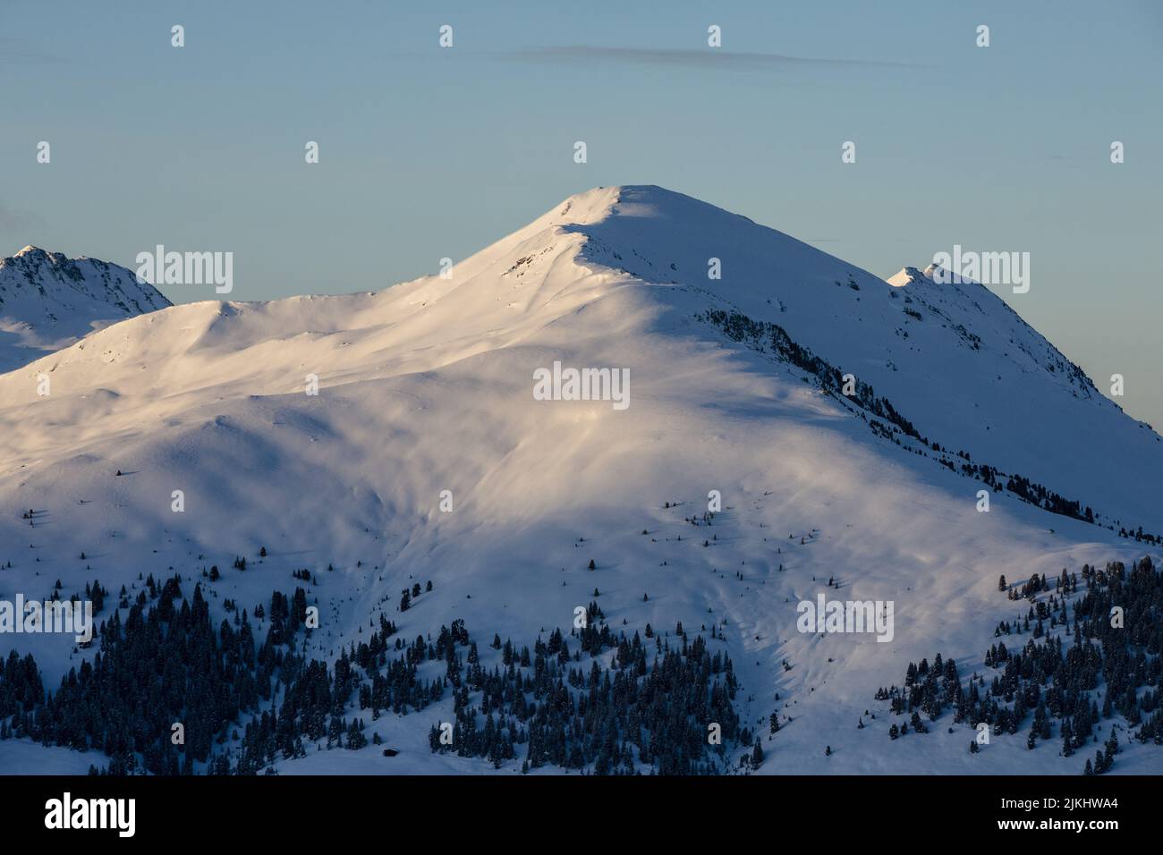 Una vista sulle montagne innevate che si illuminano alla luce del sole Foto Stock