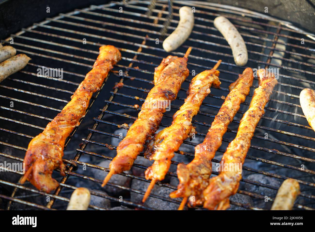 Un primo piano di deliziosi kebab shish che cucinano su una griglia con piccole salsicce accanto a loro Foto Stock