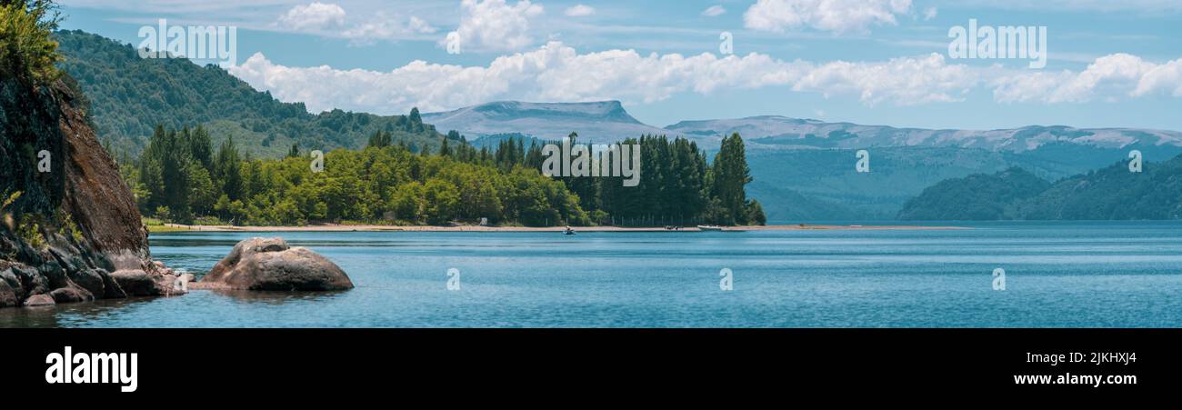Una vista panoramica del mare circondato da alberi e montagne ad alta densità sullo sfondo Foto Stock