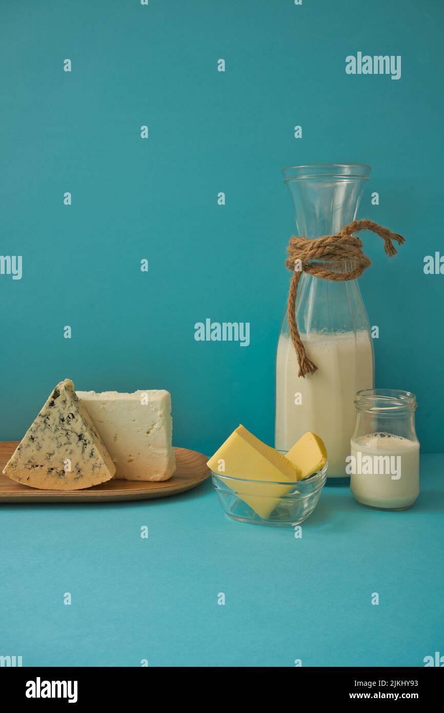 Diversi latticini su sfondo blu: Yogurt, formaggio, latte e uova. Vitamine solubili in acqua (B1, B2, niacina e acido folico) e solubili nei grassi v Foto Stock