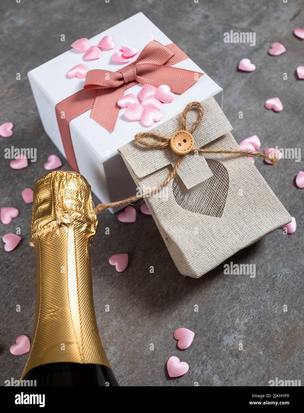 San Valentino sfondo con cuori, confezione regalo, champagne. Sullo sfondo della tavola in pietra grigia, vista dall'alto Foto Stock