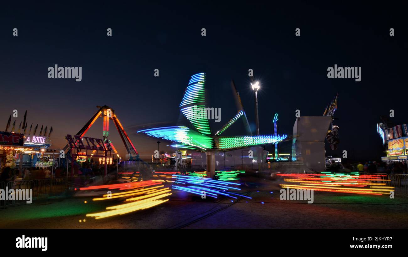 Una collezione di giostre in una fiera della contea di notte. Foto Stock