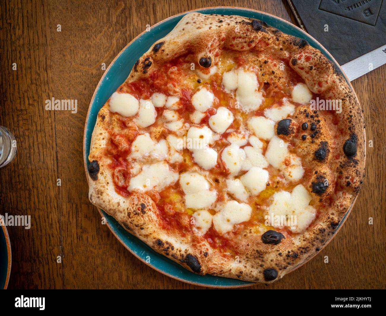 Una vista dall'alto di una deliziosa pizza margherita su un tavolo di legno Foto Stock