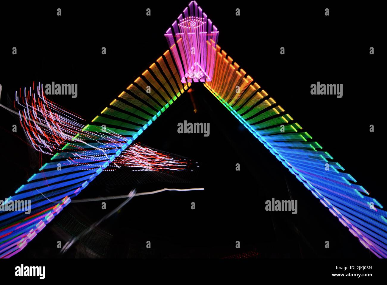 Una collezione di giostre in una fiera della contea di notte. Foto Stock