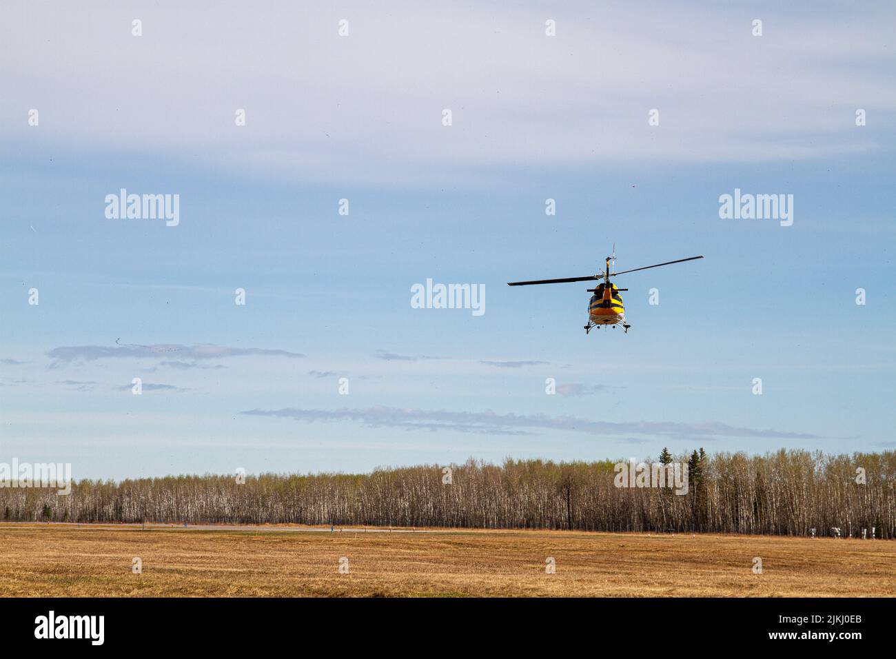 Un'inquadratura ad angolo basso di un elicottero giallo che sorvola il lago Footner in Alberta Foto Stock
