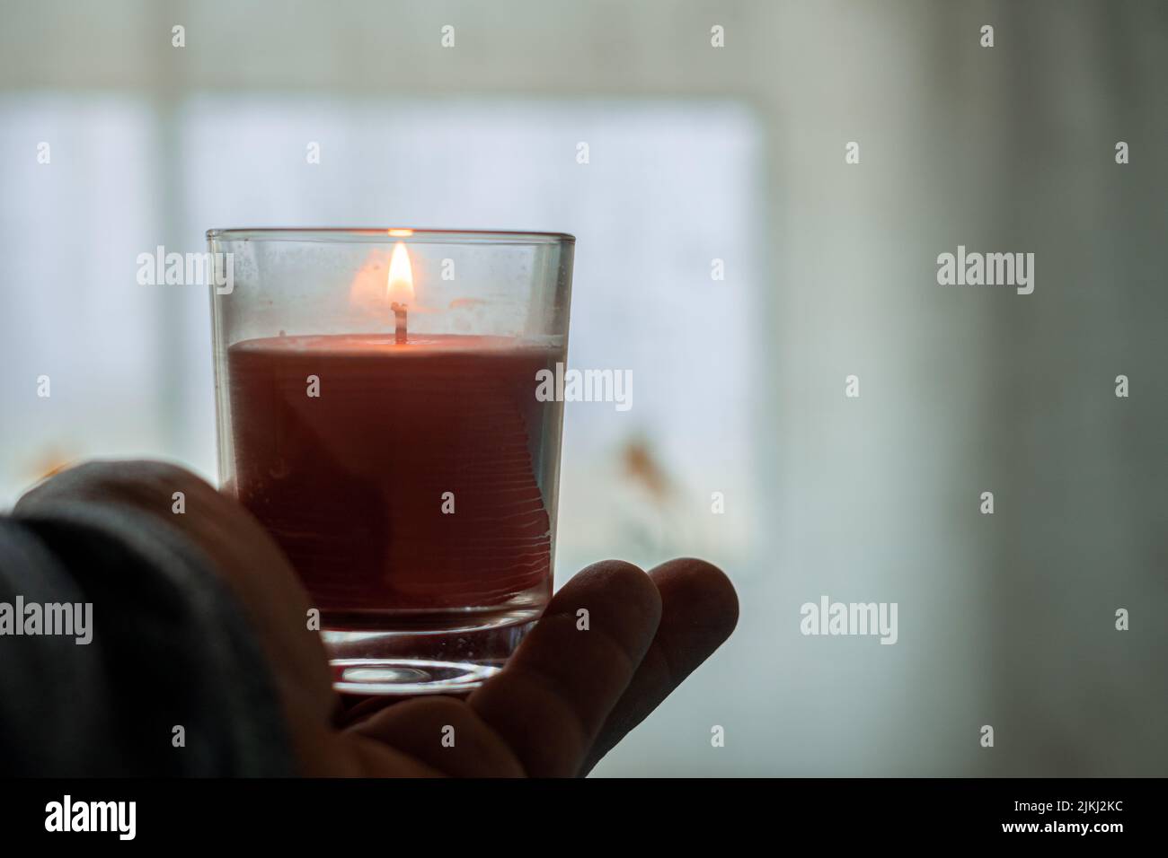 Una candela accesa in vetro trasparente sul palmo della mano umana Foto Stock Una candela accesa in vetro trasparente sul palmo della mano umana Foto Stock