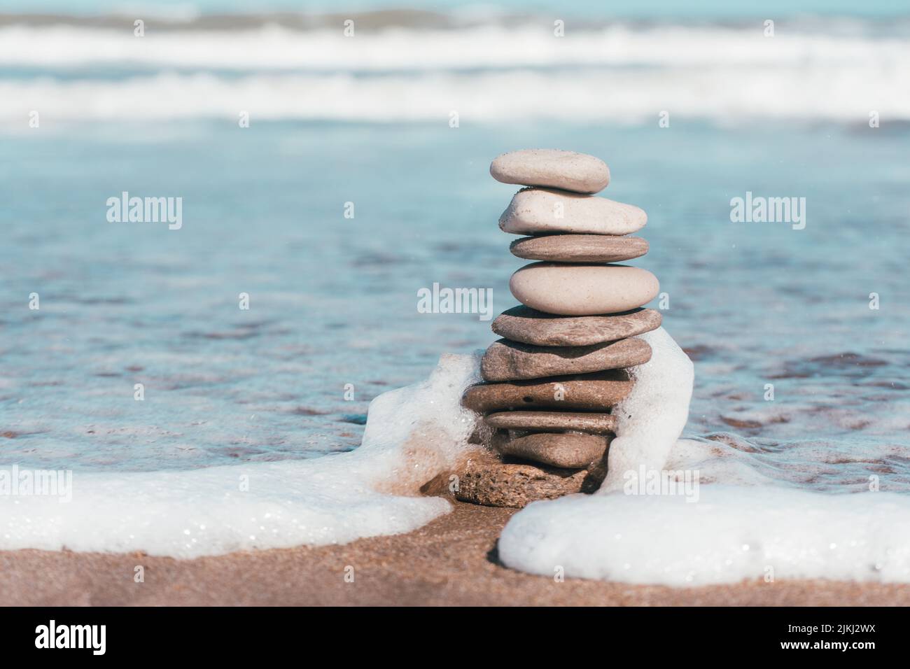 Un fuoco poco profondo di pietre della spiaggia accatastate l'una sull'altra sullo sfondo del mare schiumato Foto Stock