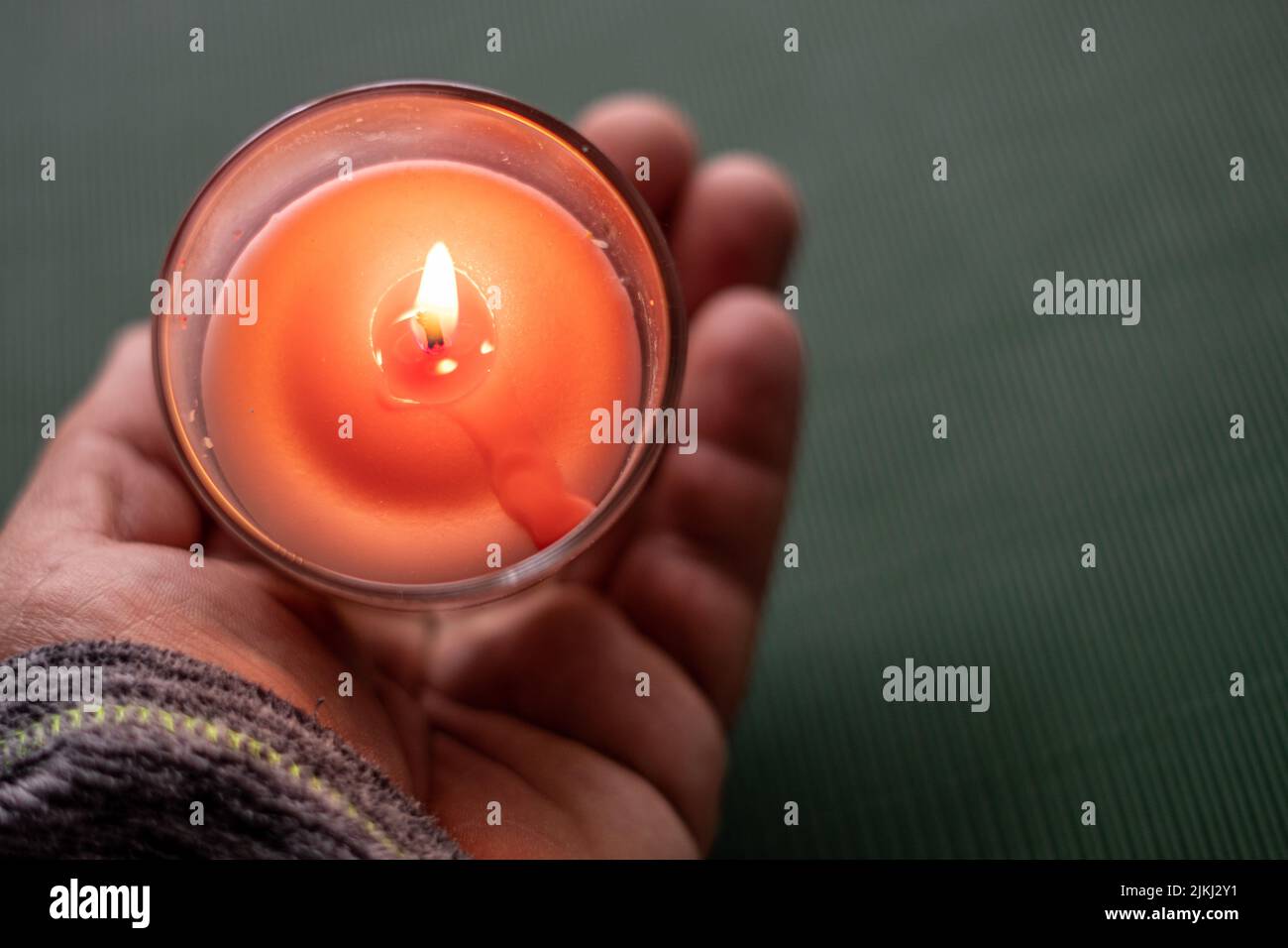 Una candela accesa in vetro trasparente sul palmo della mano umana Foto Stock Una candela accesa in vetro trasparente sul palmo della mano umana Foto Stock