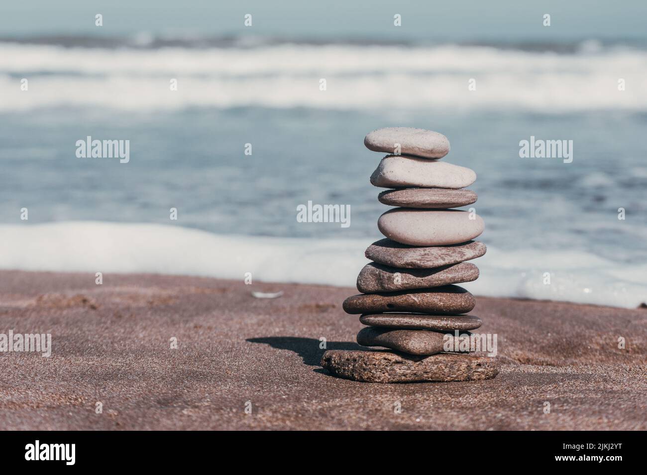 Un fuoco poco profondo di pietre della spiaggia accatastate l'una sull'altra sullo sfondo del mare schiumato Foto Stock