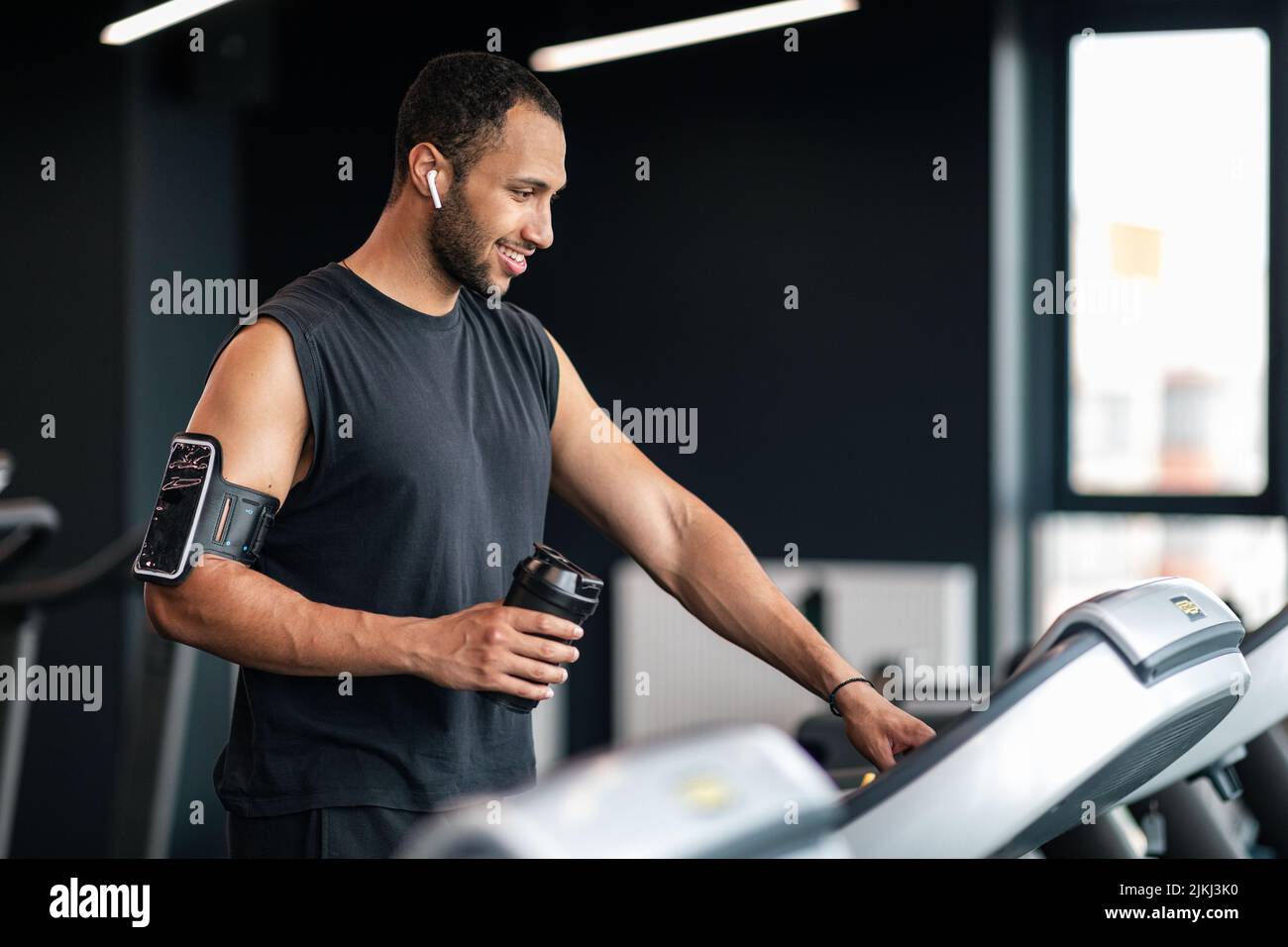 Ritratto di atleta maschio felice nero esercitandosi sul tapis roulant alla palestra, Foto Stock