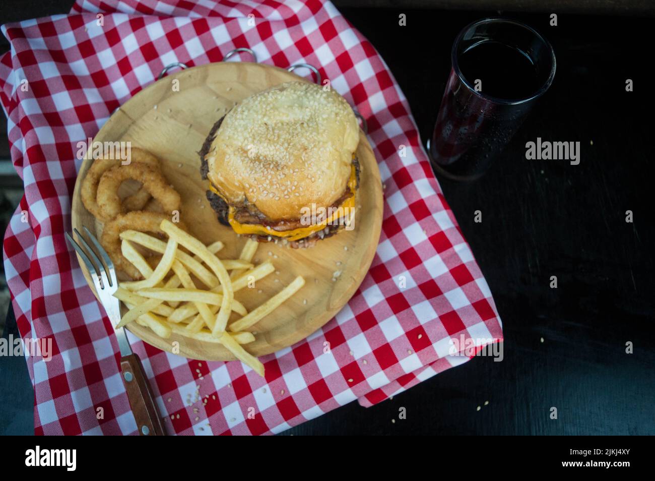 Un angolo top shot di un hamburger su un piatto con anelli di cipolla e patatine fritte sul lato. Foto Stock