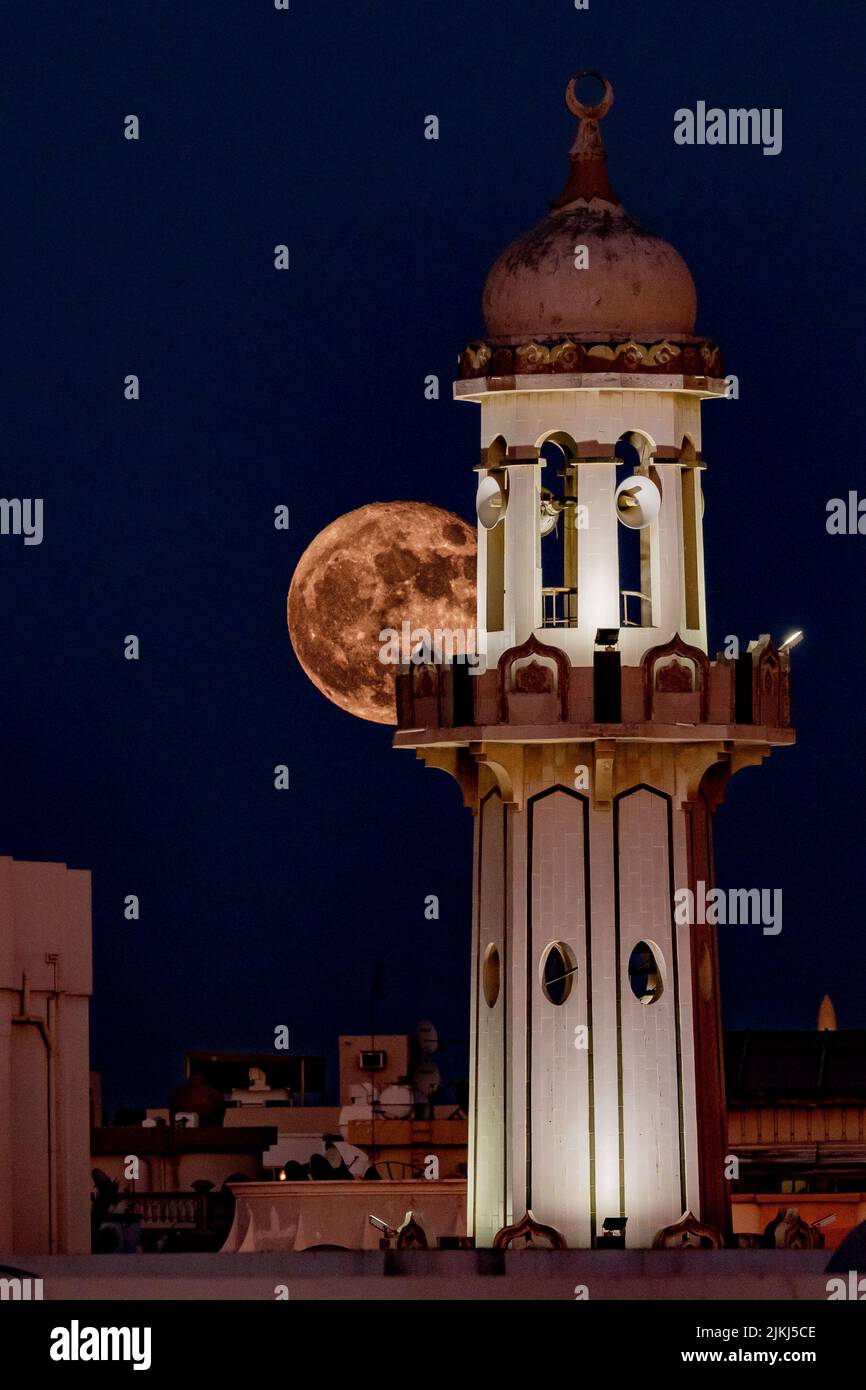 Una foto verticale di una torre con la luna sullo sfondo Foto Stock