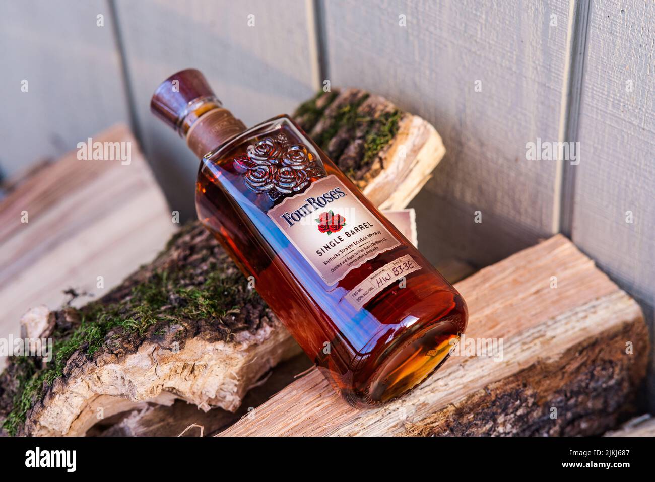 Un colpo ad angolo alto di una bottiglia di bourbon di quattro rose su mucchi di legna da ardere all'aperto Foto Stock