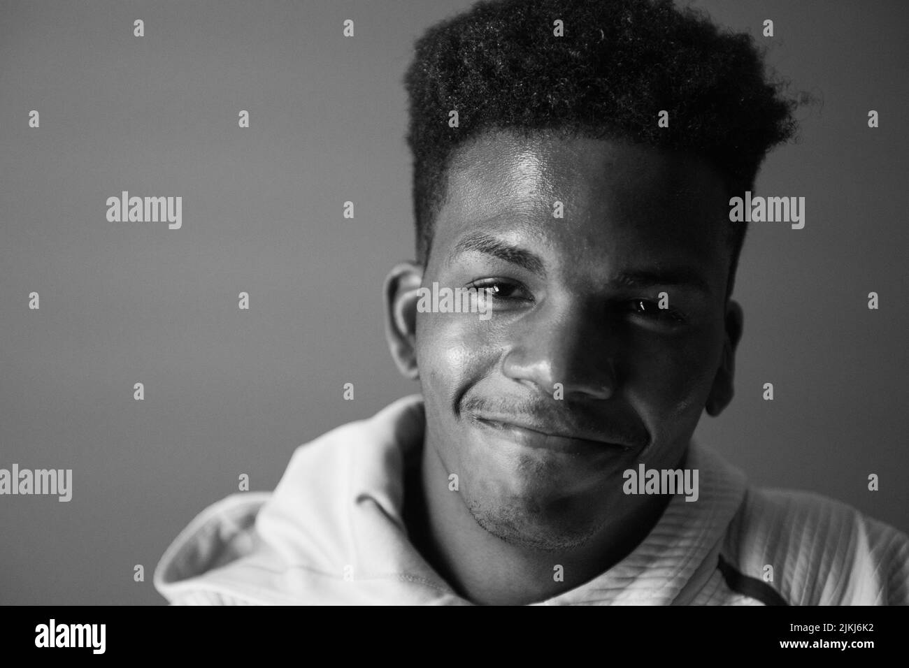 Un ritratto in scala di grigi di un uomo afroamericano sullo sfondo scuro. Foto Stock