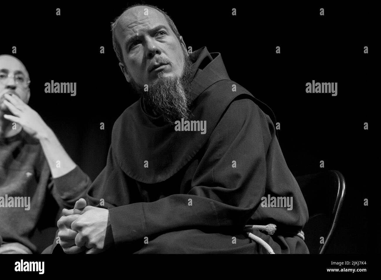 Un uomo con una barba seduta su una sedia in una discussione contro l'odio tra tutte le religioni sacre indoor. Bianco e nero Foto Stock