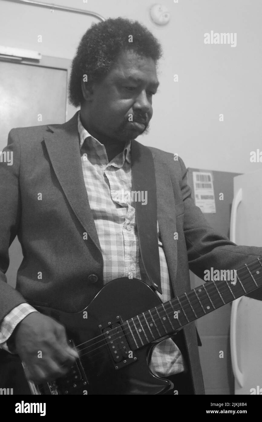 Un colpo in scala di grigi di un maschio nero che suona la chitarra Foto Stock