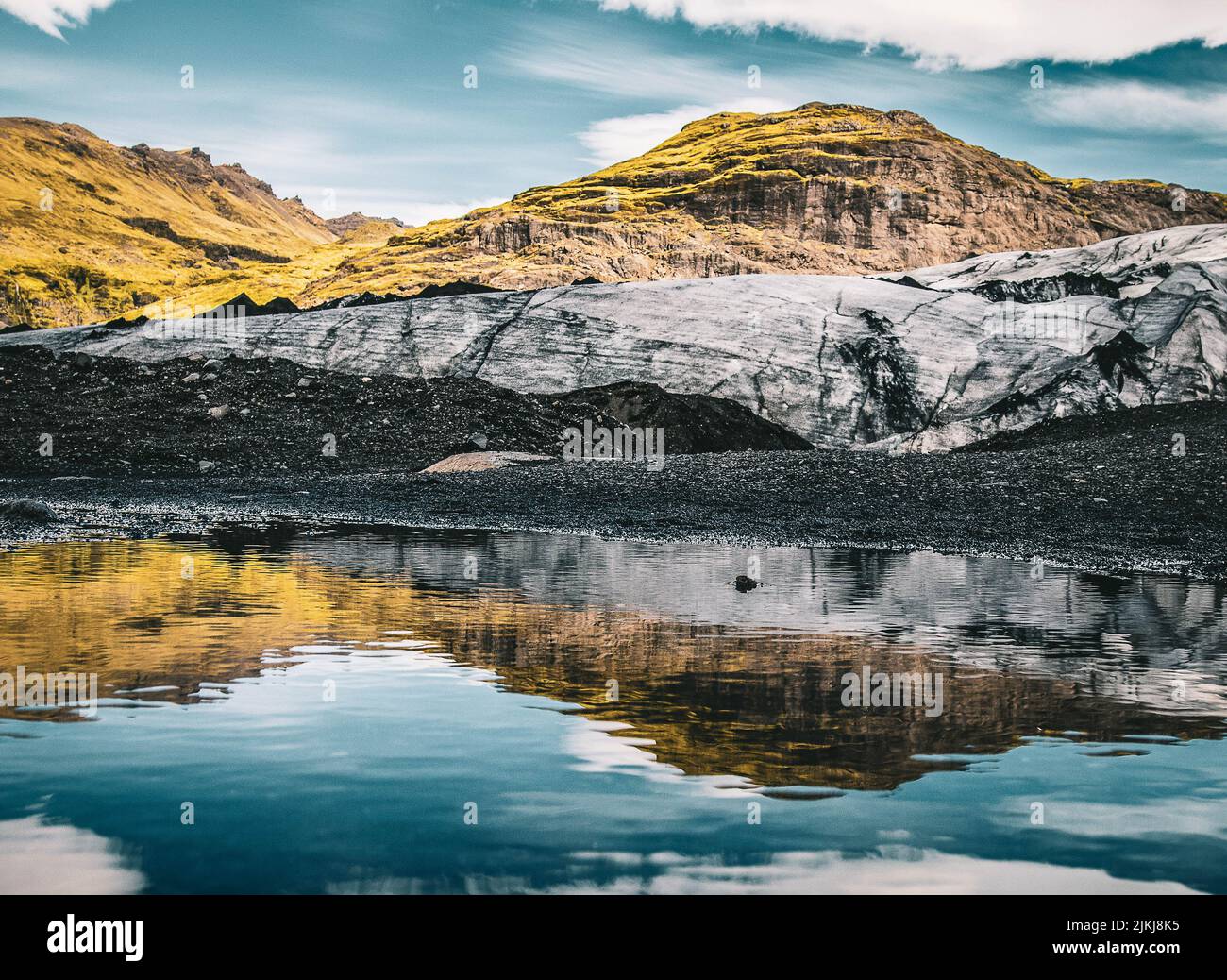 Una bella vista panoramica del ghiacciaio Solheimajokulll con riflessione visibile sull'acqua contro il cielo blu in una giornata di sole, Islanda Foto Stock